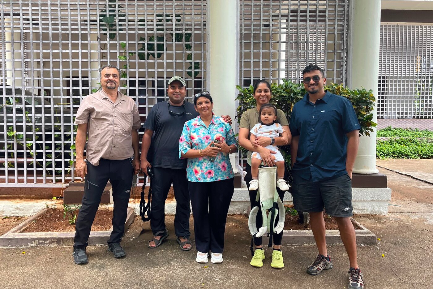 The Ross family standing together outside a white building with a lattice screen