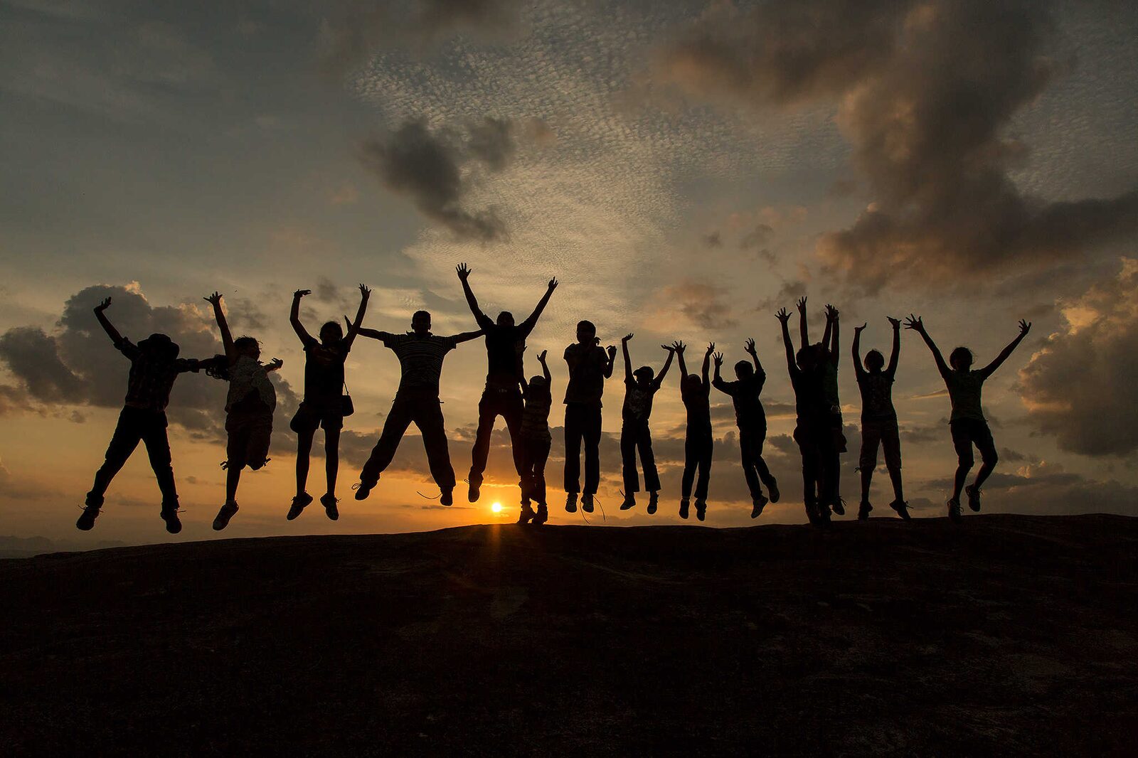 Children jumping in silhouette at sunset